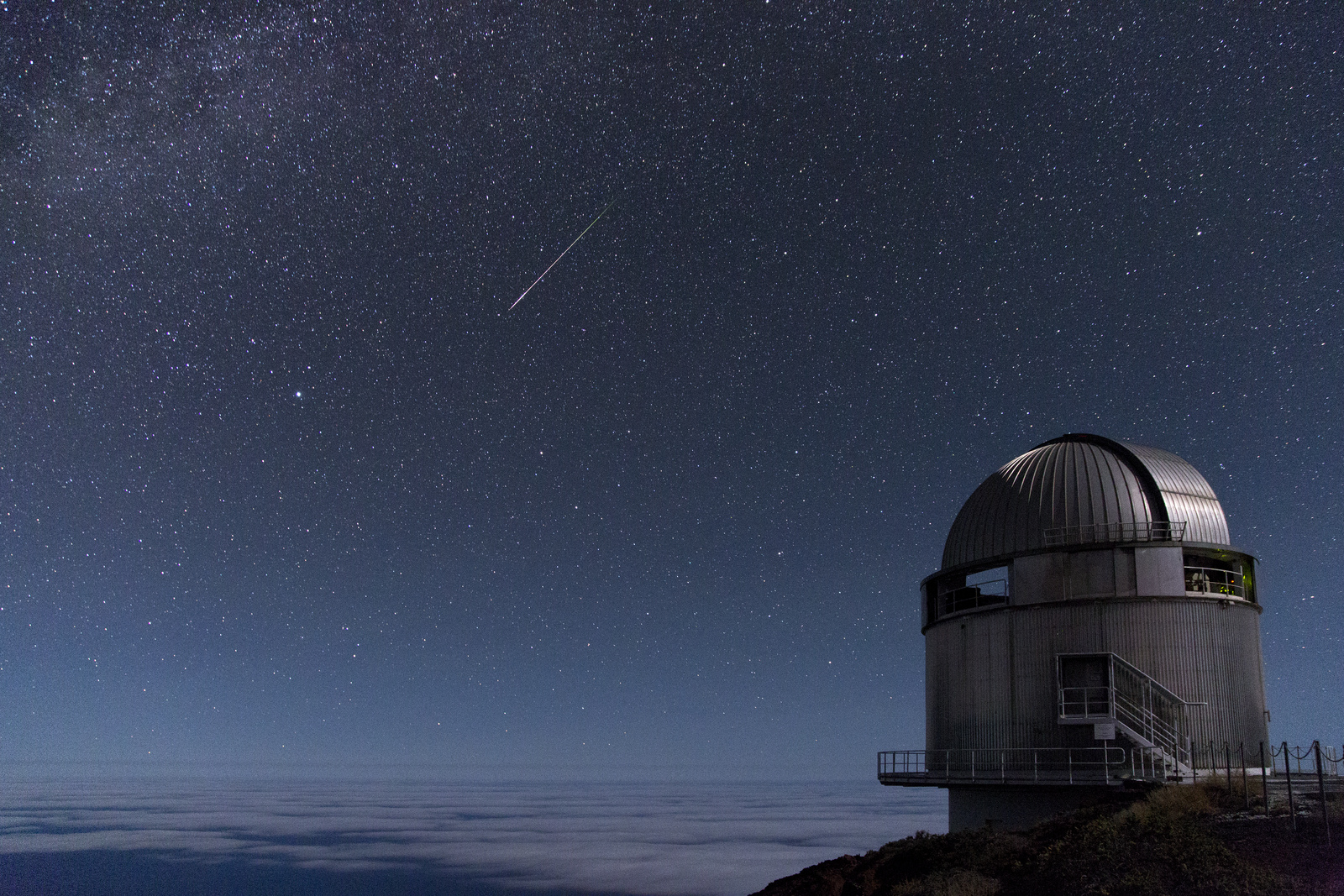 [Translate to English:] Observatoriet fotograferet en stjerneklar nat, mens en meteor trækker en hvid stribe henover himlen.