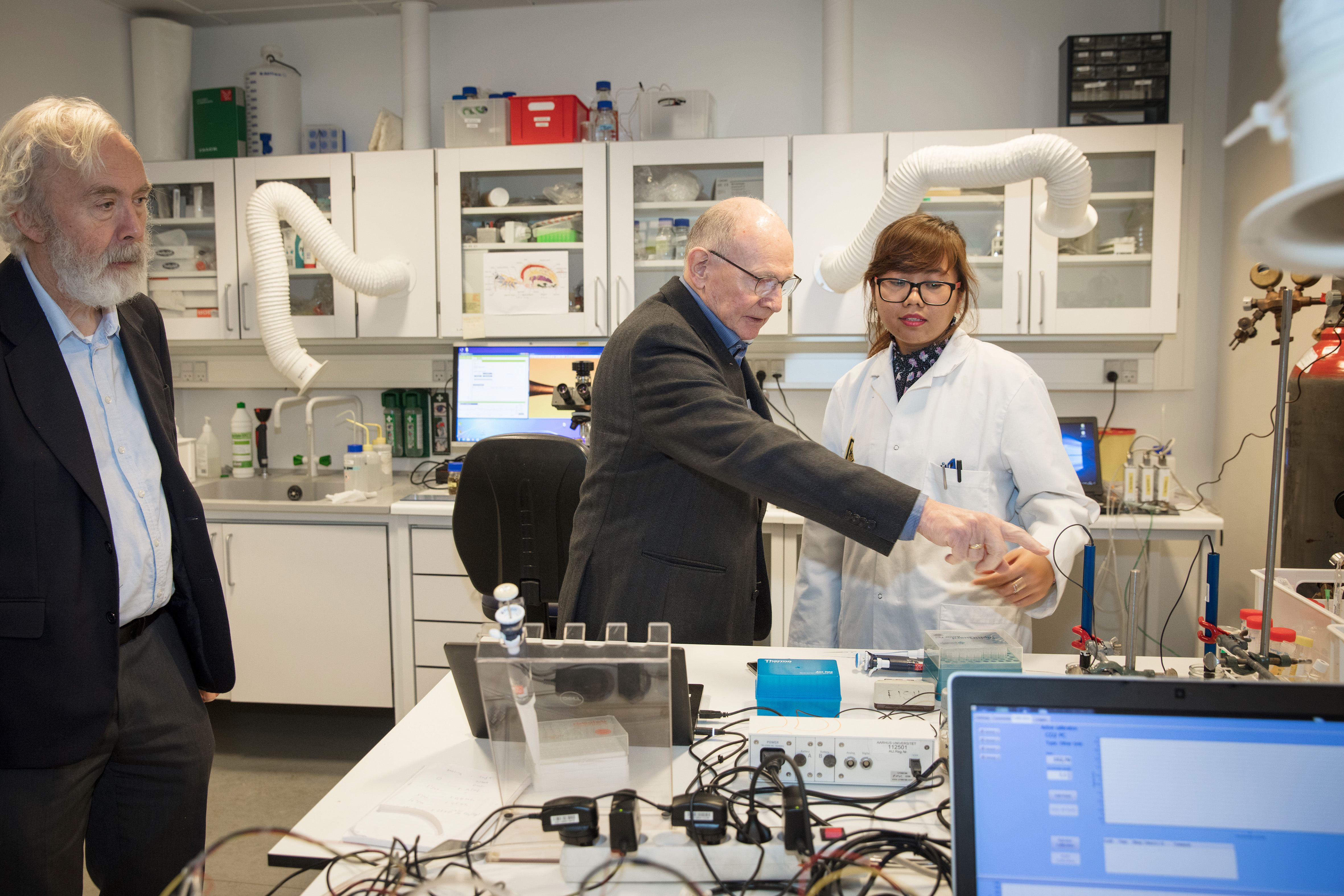 Young lady in a lab coat talking to Niels Due Jensen.